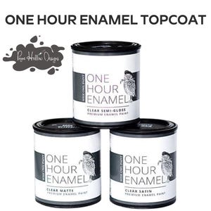 May include: Three cans of Wise Owl Paint enamel topcoat are stacked. The cans are white with black lids and feature the text "ONE HOUR ENAMEL" and an owl illustration. The text "CLEAR SEMI-GLOSS", "CLEAR MATTE", and "CLEAR SATIN" are visible.