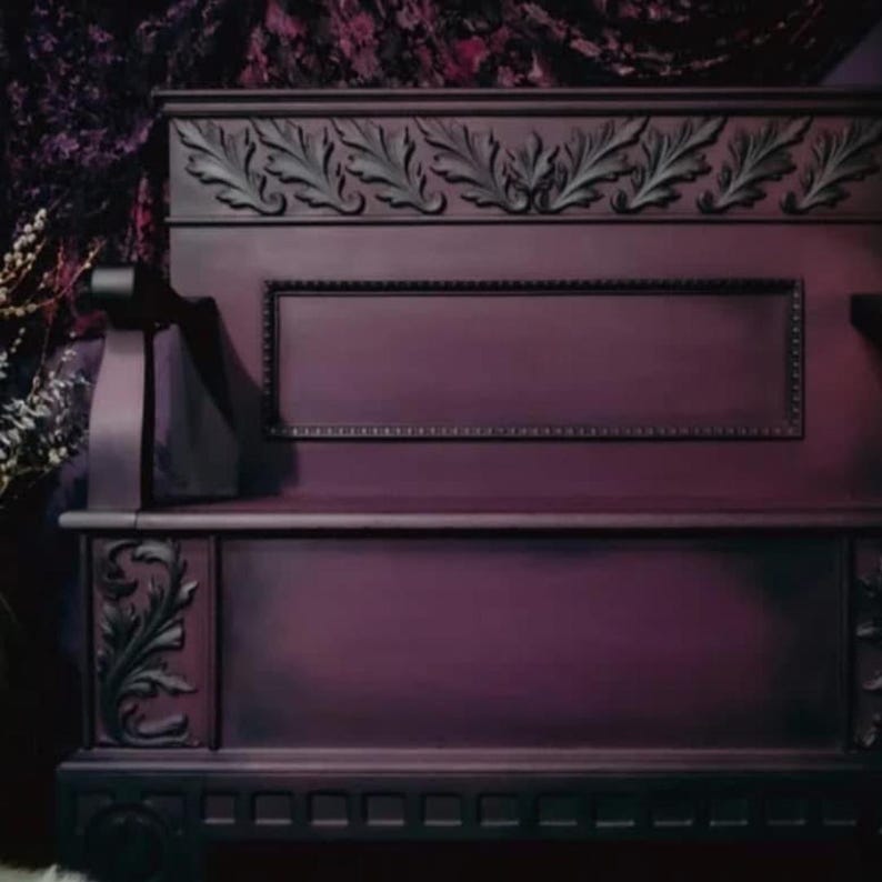 May include: A dark purple bench with ornate leaf carvings. The bench features a rectangular panel and decorative trim. The overall design is gothic and elegant, with a focus on detailed craftsmanship and a vintage aesthetic.
