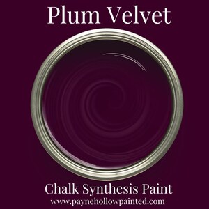 May include: A paint tin filled with Plum Velvet chalk synthesis paint. The paint is a deep purple with a swirling pattern. The tin has a silver rim and is set against a dark purple background. Text at the top reads "Plum Velvet" and at the bottom "Chalk Synthesis Paint".