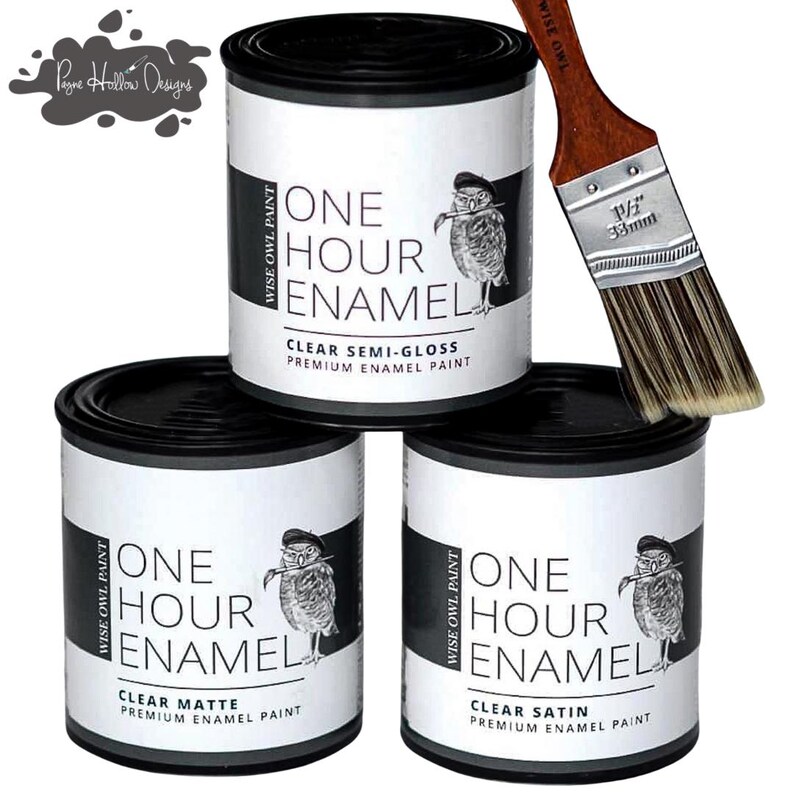 May include: Three cans of Wise Owl Paint, each with a black lid and a label featuring an owl illustration. The labels read "One Hour Enamel" with different finishes: Clear Matte, Clear Semi-Gloss, and Clear Satin. A 1 1/4" (33mm) paintbrush rests on the cans.