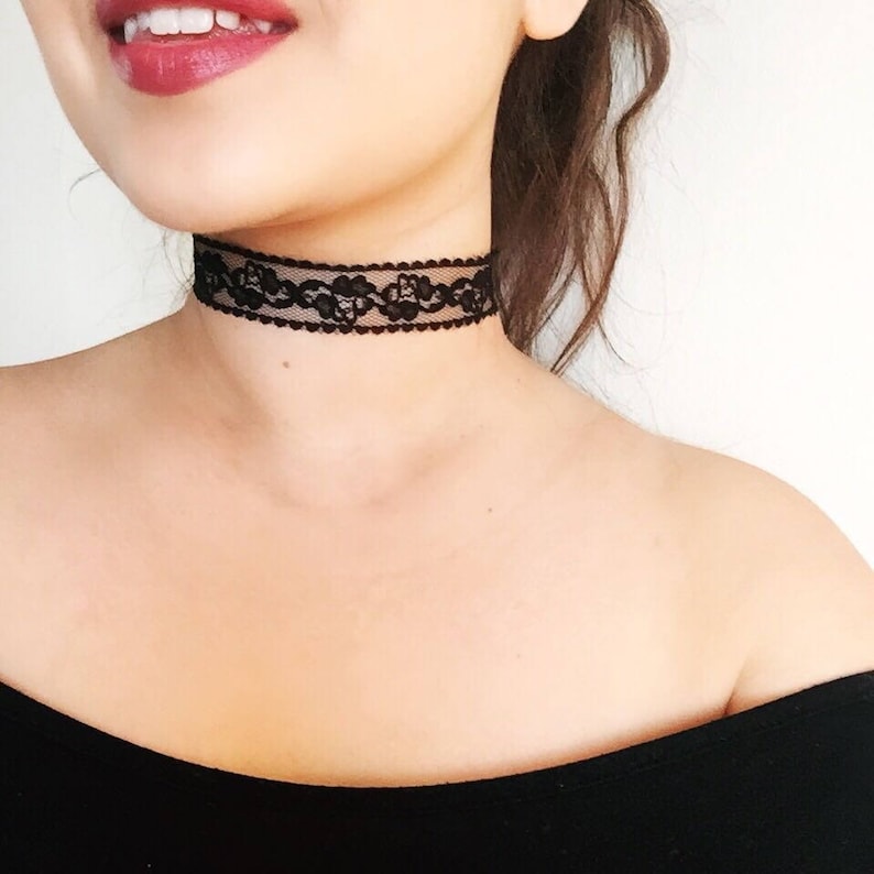 May include: A black lace choker necklace with a floral design. The choker is worn around the neck and is made of delicate, intricate lace. The necklace is a stylish accessory.