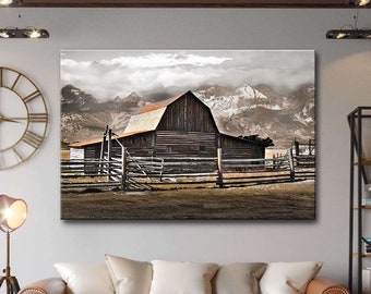 May include: A rustic wooden barn with a red roof sits in a field with a wooden fence. The barn is surrounded by snow-capped mountains in the background. The sky is cloudy and gray.