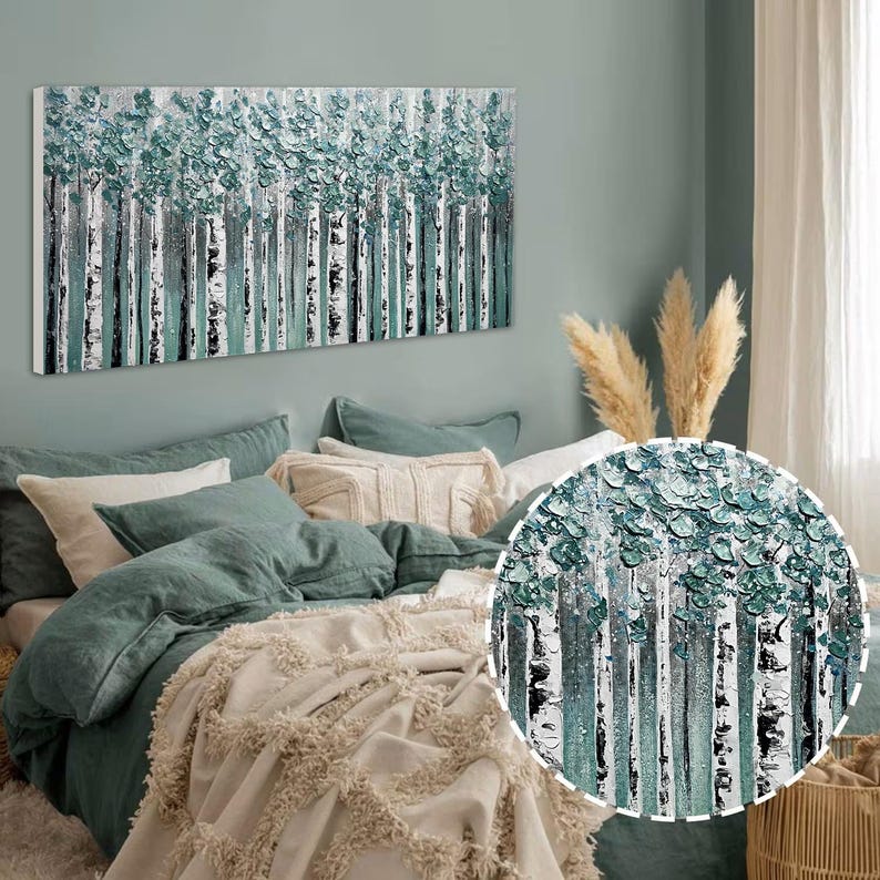 Op de afbeelding: Een rechthoekig canvas kunstwerk met een berkenbos. Het kunstwerk maakt gebruik van getextureerde turquoise en witte verf, met zwart-witte boomstammen. Het kunstwerk hangt boven een bed met turquoise beddengoed en een cr&egrave;mekleurige sprei.