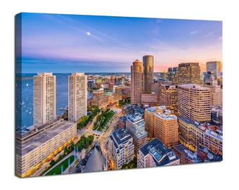 May include: An aerial view of the Boston skyline at sunset. The city is illuminated by the setting sun, casting a warm glow over the buildings. The water in the harbor is calm and reflects the sky.