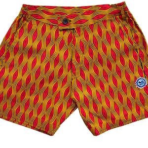 Puede incluir: Bañador rojo y amarillo con estampado y un pequeño logotipo azul en la pierna derecha.