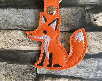Könnte beinhalten: Orangener Filz-Fuchs-Schlüsselanhänger mit einem silbernen Schlüsselring. Der Fuchs hat einen weißen gestickten Bauch und Schwanz.