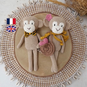 Peut inclure: Deux jouets en crochet en forme de singe, l'un portant une écharpe jaune et un sac à main brun avec un cœur rose, l'autre portant un nœud papillon à imprimé léopard. Les jouets sont assis sur un tapis rond tissé avec un motif blanc et brun.