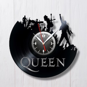Könnte beinhalten: Schwarze Vinyl-Schallplattenuhr mit einer Band-Silhouette, einschließlich eines Sängers mit Mikrofon. Das Wort "QUEEN" ist in Silber dargestellt. Die Uhrzeiger sind schwarz mit einem roten Sekundenzeiger. Ein dekorativer Artikel.
