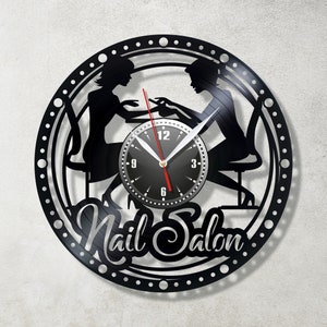May include: Black vinyl record clock with a silhouette of two people getting their nails done. The clock face is black with white numbers and hands. The text "Nail Salon" is written in a decorative font below the clock face.