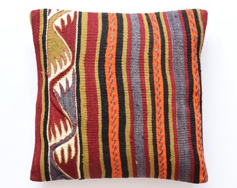 May include: A colorful striped pillow with a geometric pattern on one side. The pillow is made of woven fabric and has a rustic, hand-crafted look.