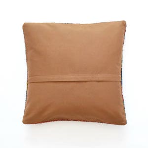 May include: A brown throw pillow with a colorful patterned back. The pillow has a zipper closure and a brown fabric backing.
