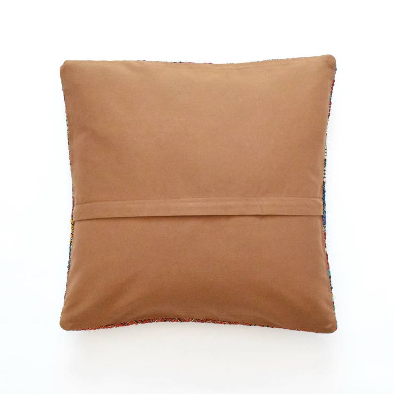 May include: A brown throw pillow with a colorful patterned back. The pillow has a zipper closure and a brown fabric backing.