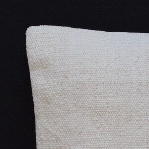 May include: Close-up of a white linen pillow cover with a textured weave. The pillow cover is soft and comfortable, perfect for adding a touch of elegance to any room.