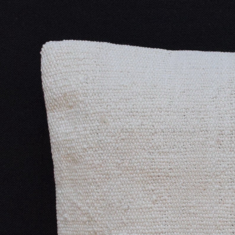 May include: Close-up of a white linen pillow cover with a textured weave. The pillow cover is soft and comfortable, perfect for adding a touch of elegance to any room.
