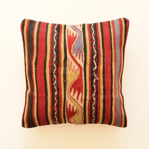 Peut inclure: Un coussin de décoration rayé rouge, noir et jaune avec un motif tissé. Le coussin présente un design traditionnel avec un motif répétitif d'oiseaux stylisés.