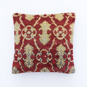 May include: Red and cream patterned throw pillow with a floral design. The pillow is made of a soft, woven fabric.