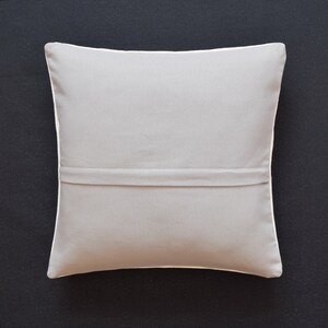 May include: A plain gray throw pillow with a white border and a zipper closure on the back.