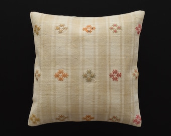 May include: A white pillow with a beige and white striped pattern and embroidered floral designs in shades of orange, pink, and green.