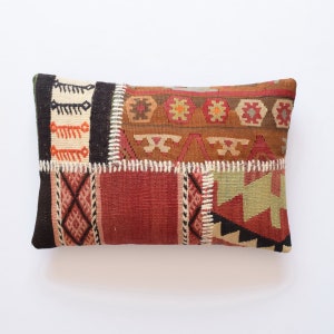 May include: A rectangular patchwork cushion featuring a range of geometric patterns in shades of red, brown, green, and white. The cushion is crafted from woven fabric and has a hand-stitched look.
