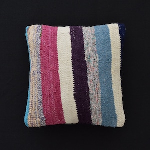 Peut inclure: Un coussin rayé avec un motif blanc, rose, bleu et violet. Le coussin est fait d'un tissu tissé avec une surface texturée.
