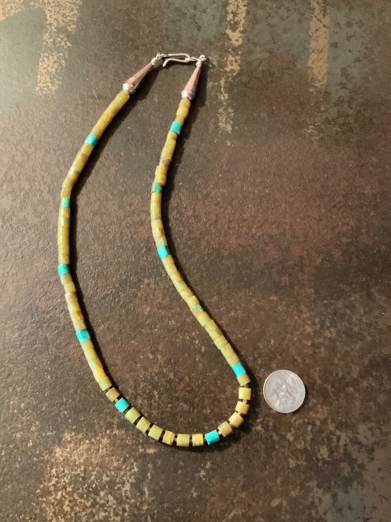 May include: A necklace made of light green and turquoise square beads with silver clasps. A US quarter is included for scale.