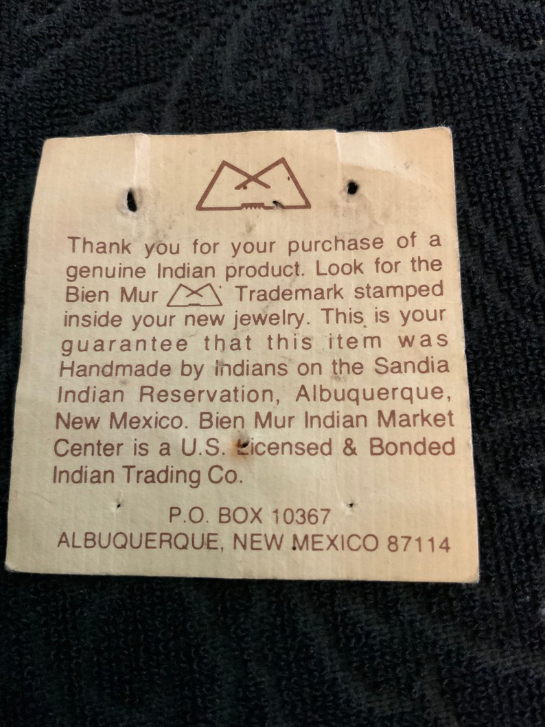 May include: A white tag with brown text that reads "Thank you for your purchase of a genuine Indian product. Look for the Bien Mur Trademark stamped inside your new jewelry. This is your guarantee that this item was Handmade by Indians on the Sandia Indian Reservation, Albuquerque, New Mexico. Bien Mur Indian Market Center is a U.S. Licensed & Bonded Indian Trading Co. P.O. BOX 10367 ALBUQUERQUE, NEW MEXICO 87114"
