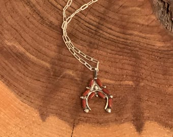Op de afbeelding: Een zilveren ketting met een rode koraal hoefijzer hanger. De hanger is gemaakt van sterling zilver en heeft een traditioneel Native American ontwerp.