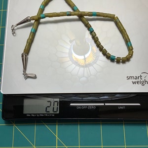 May include: A green and turquoise beaded necklace with silver clasps, weighing 20 grams on a digital scale.
