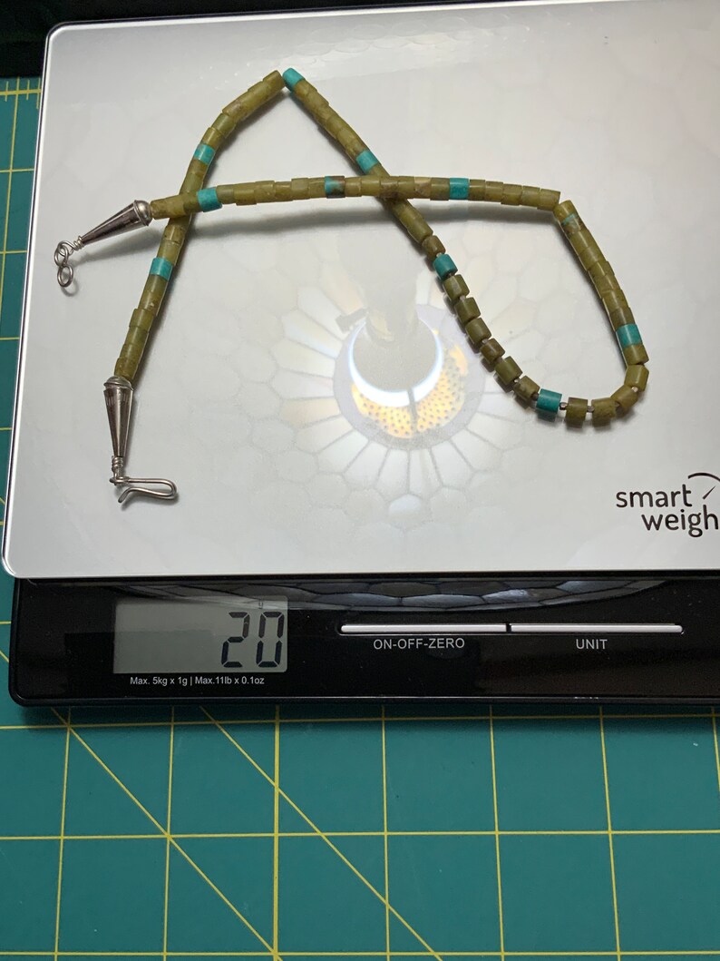 May include: A green and turquoise beaded necklace with silver clasps, weighing 20 grams on a digital scale.