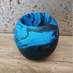 May include: A small, round planter made of blue and black marbled resin. The planter has a smooth, glossy finish.