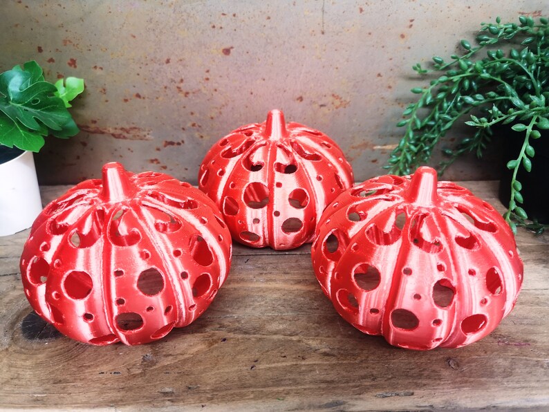 May include: Three red and white pumpkin-shaped candle holders with a cut-out design.
