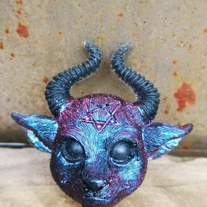 Puede incluir: Una peque&ntilde;a escultura de resina azul y roja de un demonio con cuernos y un pentagrama en la frente.