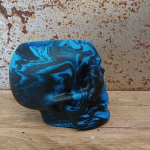 May include: A blue and black marbled skull planter. The skull is made of a smooth, hard material and has a detailed design.