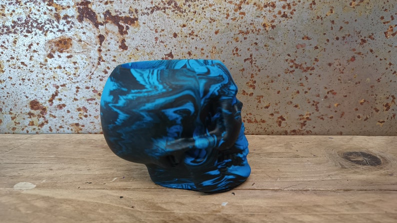 May include: A blue and black marbled skull planter. The skull is made of a smooth, hard material and has a detailed design.