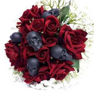 May include: A bouquet of deep red roses with black skull accents. The roses are arranged in a circular shape and the skulls are scattered throughout the bouquet.