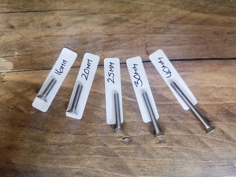 May include: Five silver screws of varying lengths, labelled with their measurements in millimetres: 16mm, 20mm, 25mm, 30mm, and 40mm.