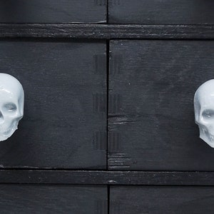 May include: Black dresser with white ceramic skull drawer pulls.