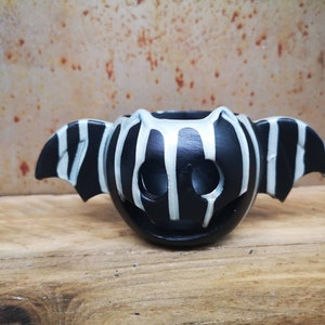 May include: Black and white striped ceramic bat planter with white dripping paint accents.