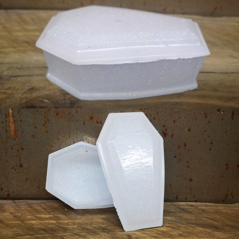 May include: A set of three white coffin-shaped boxes with a glittery finish. The boxes are made of resin and are perfect for storing small items.