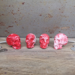 May include: Four red and white skull-shaped drawer pulls with a marbled effect. Each pull has a silver screw and washer.