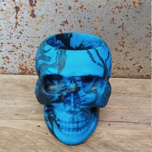 May include: A blue and black skull-shaped planter with a marbled design.