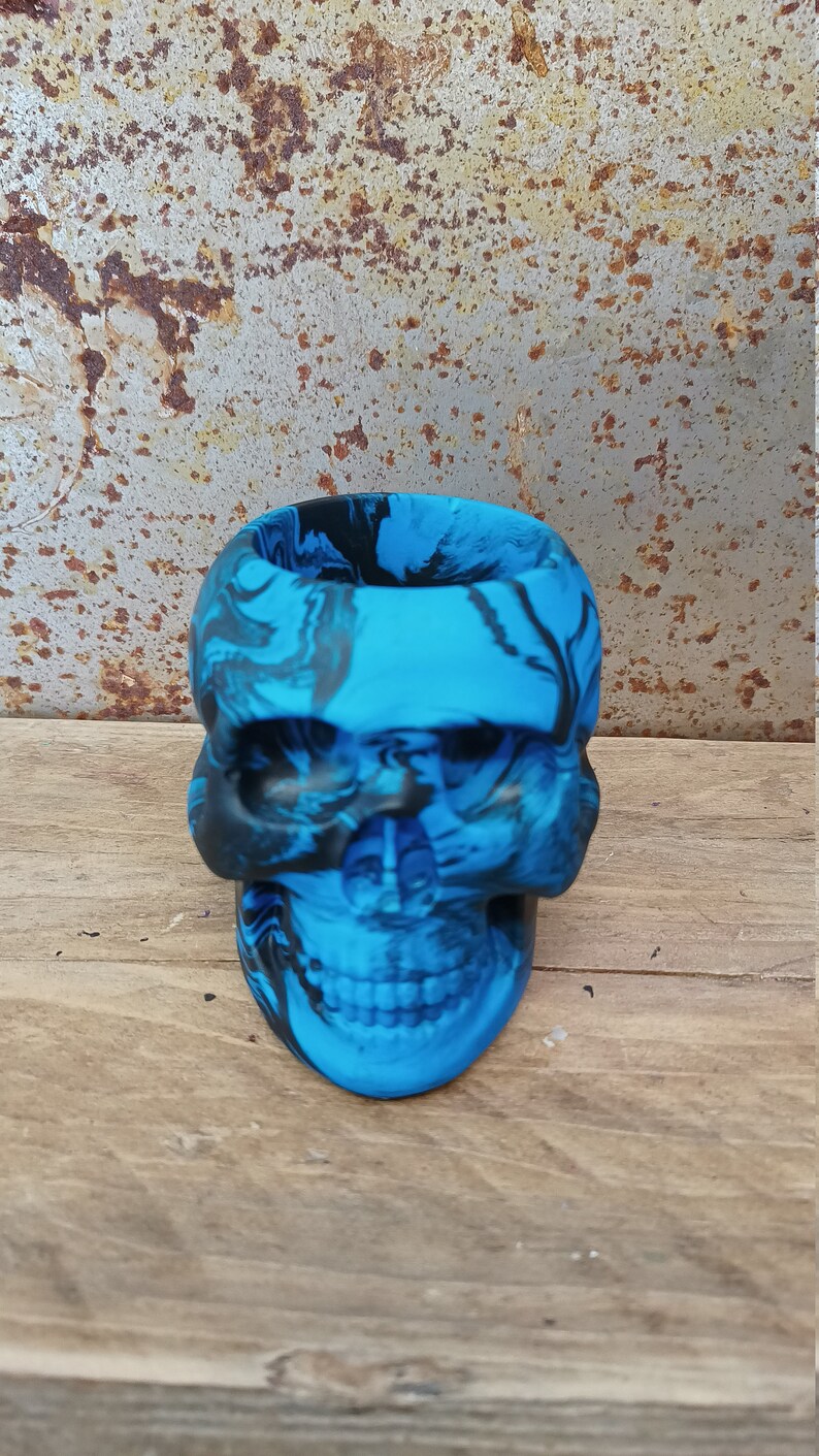 May include: A blue and black skull-shaped planter with a marbled design.