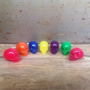 May include: Seven colourful skull-shaped drawer pulls in red, orange, yellow, green, blue, purple and pink.