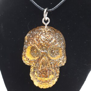 May include: A gold glitter skull pendant necklace with a black cord.