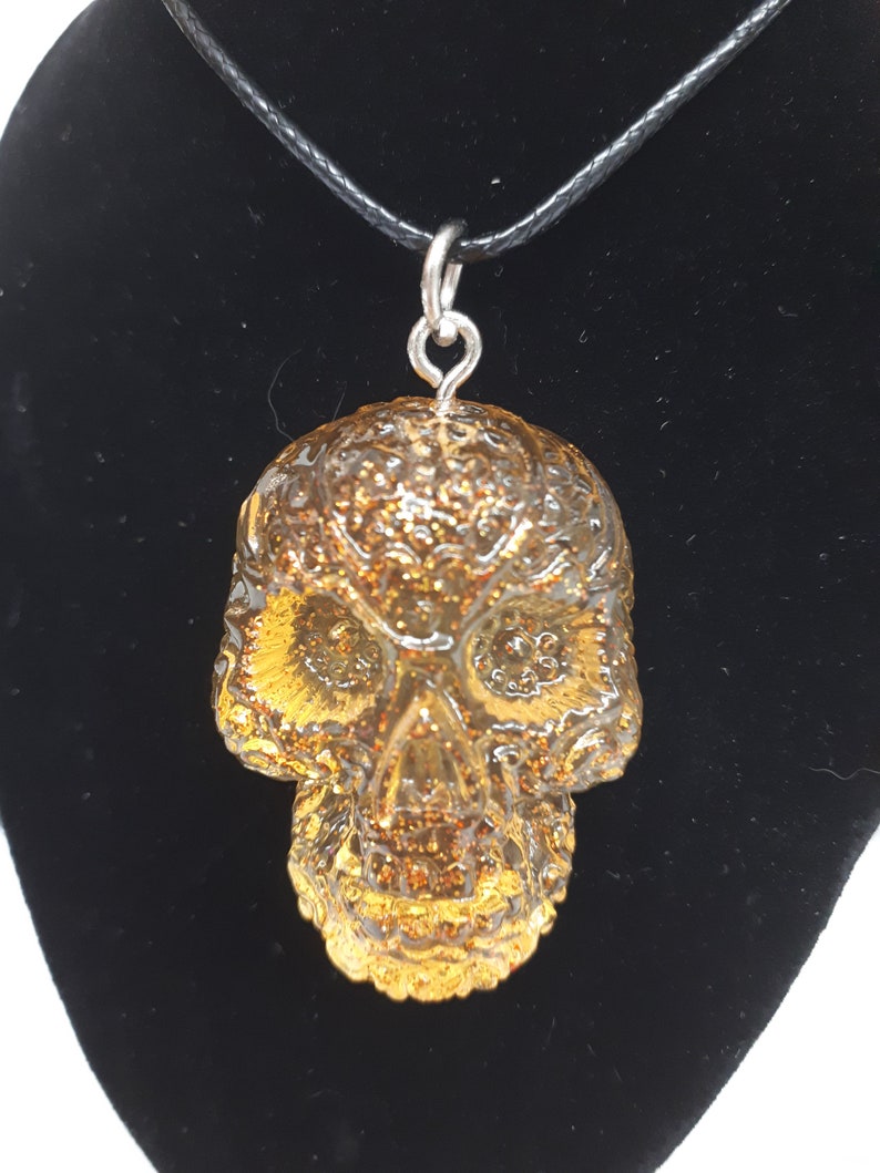 May include: A gold glitter skull pendant necklace with a black cord.