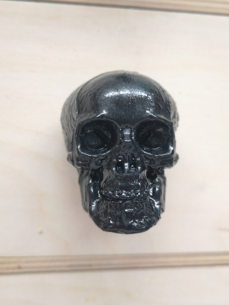 May include: A black skull-shaped door knob with a detailed design. The skull has a glossy finish.