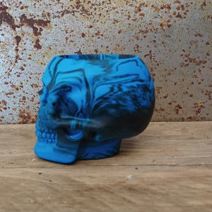 May include: A blue and black skull-shaped planter with a marbled design.
