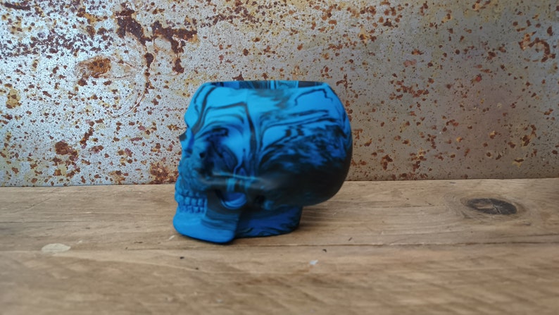 May include: A blue and black skull-shaped planter with a marbled design.