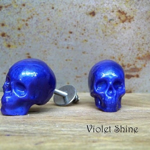 May include: Two purple skull-shaped drawer pulls with a shiny finish. The pulls are on a wooden surface with the text "Violet Shine" below them.
