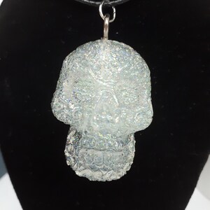 May include: A silver glitter skull pendant necklace with a black cord.